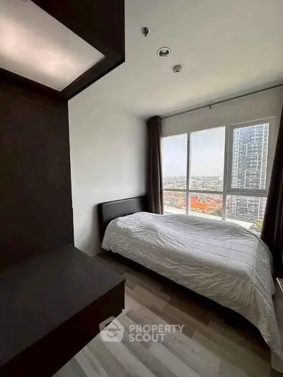 Modern bedroom with large window offering stunning city view in high-rise apartment.