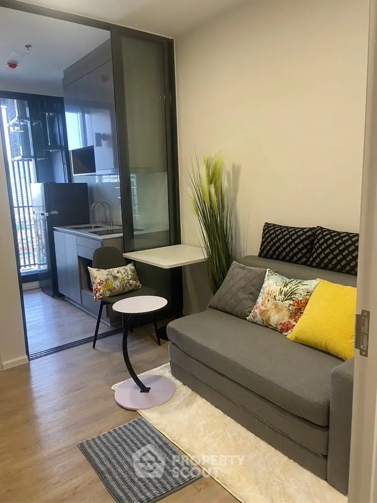 Modern compact living room with stylish decor and adjacent kitchen area in urban apartment.