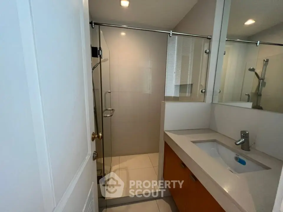 Modern bathroom with glass shower and sleek vanity in a contemporary home.