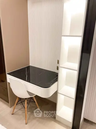 Modern study nook with sleek black marble desk and white shelving in stylish apartment.