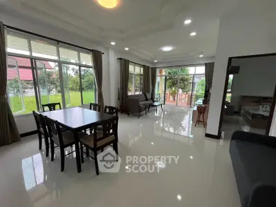 Spacious open-plan living and dining area with large windows and garden view.