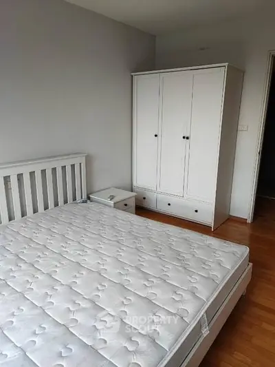 Spacious bedroom with white furniture and hardwood floors, perfect for a cozy retreat.