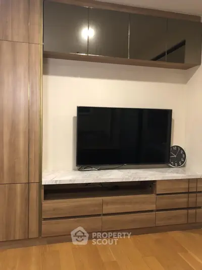 Modern living room with sleek wooden cabinetry and mounted flat-screen TV.