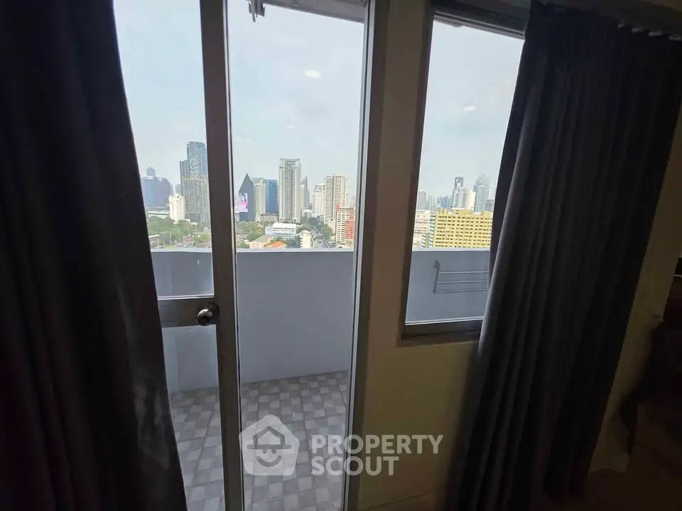 Stunning city view from modern apartment balcony with glass door access.