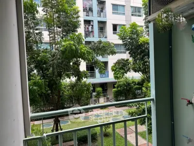 Charming balcony view overlooking lush garden in modern apartment complex.