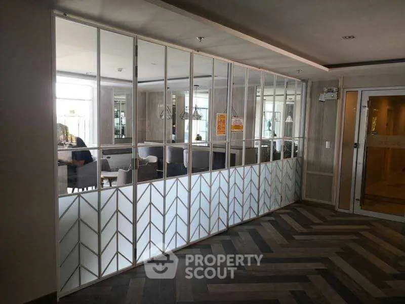 Stylish modern interior with glass partition and herringbone flooring in a shared building area.