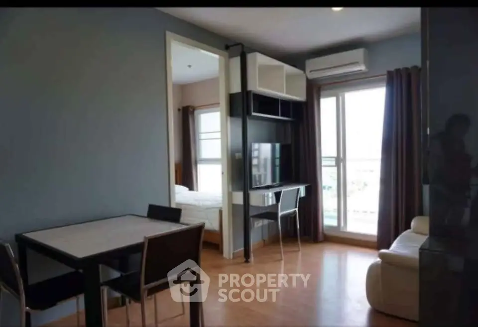 Modern apartment interior with open layout, featuring dining area, workspace, and bedroom access.