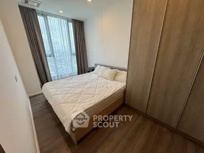 Modern bedroom with wooden flooring and large window offering city view