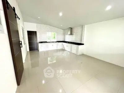 Spacious modern kitchen with sleek white cabinetry and glossy tiled flooring.