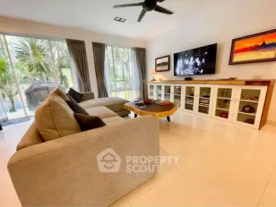 Spacious living room with modern decor and large windows offering garden views.