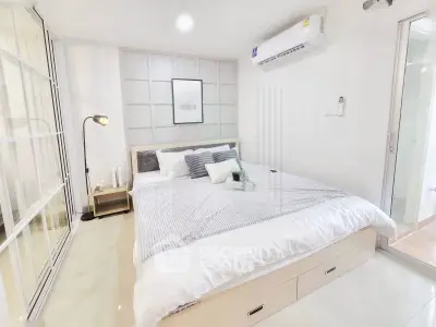 Modern bedroom with stylish decor and ample natural light, featuring a cozy bed and sleek air conditioning unit.