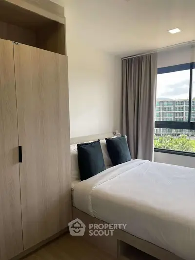 Modern bedroom with large window and stylish decor in a high-rise apartment.