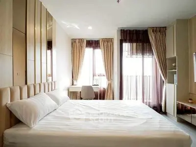 Modern bedroom with large windows and balcony access, featuring elegant decor and ample natural light.