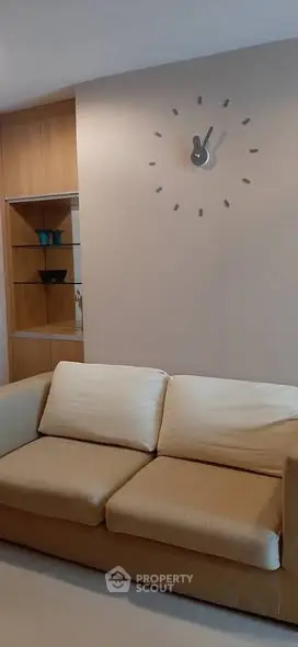 Modern living room with beige sofa and stylish wall clock, perfect for cozy relaxation.