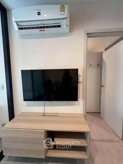 Modern living room with wall-mounted TV and air conditioning unit, featuring sleek wooden furniture.