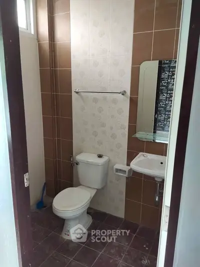 Compact bathroom with modern fixtures and tiled walls, ideal for efficient space utilization.