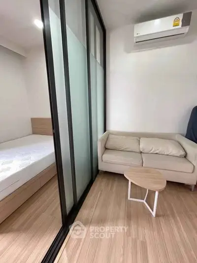 Modern studio apartment with sliding glass partition and cozy furniture