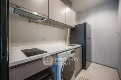 Modern kitchen with sleek appliances and washer in compact layout