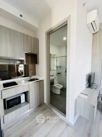 Modern compact kitchen with integrated appliances and adjacent bathroom in a stylish apartment.
