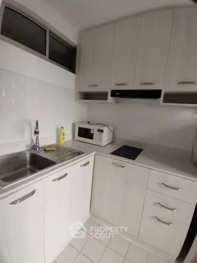 Compact modern kitchen with white cabinets and built-in appliances