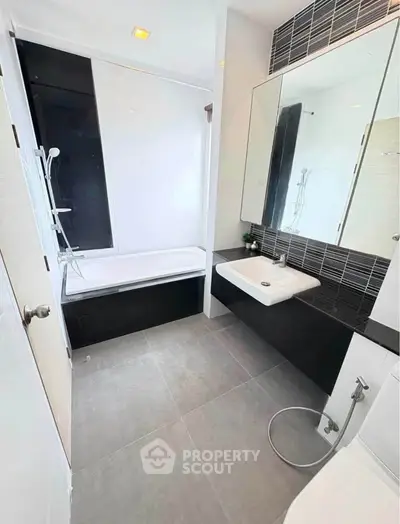 Modern bathroom with sleek design, featuring a bathtub and stylish fixtures.