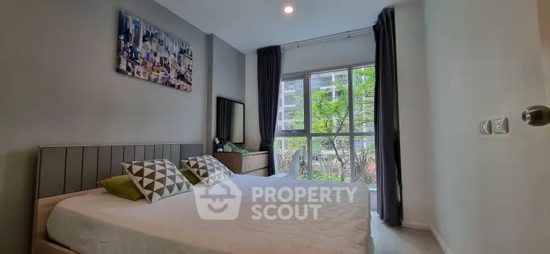 Modern bedroom with large window and stylish decor in urban apartment.