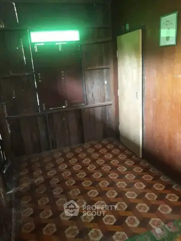 Rustic wooden room with patterned floor tiles and a closed door, ideal for creative renovation.