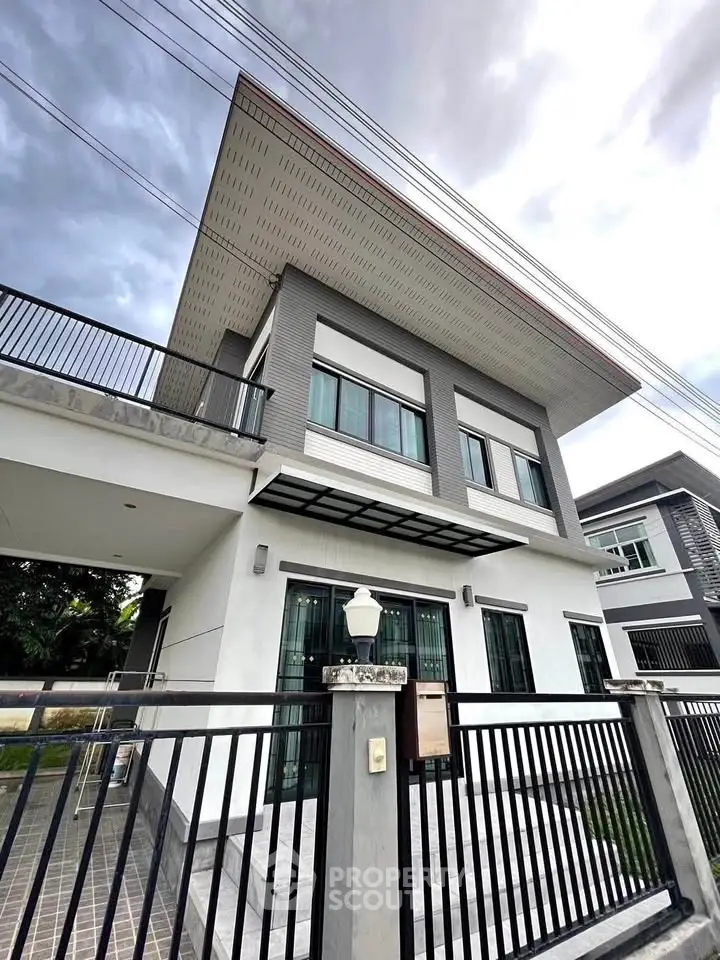 Modern two-story house with sleek design and spacious balcony in a suburban neighborhood.
