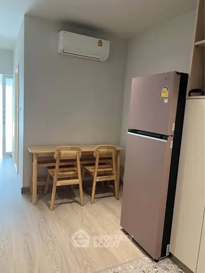 Cozy dining area with modern fridge and air conditioning in compact apartment.