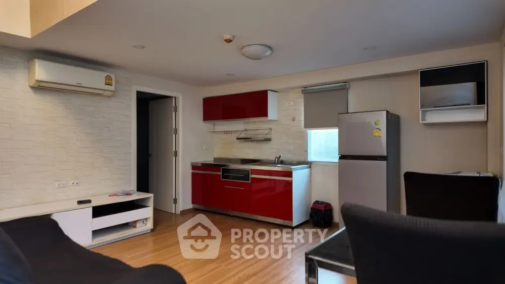 Modern apartment kitchen with red cabinets and wooden flooring