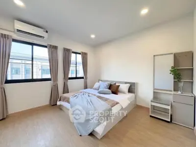 Spacious bedroom with modern decor and large windows for natural light.