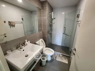 Modern bathroom with glass shower and sleek fixtures in contemporary apartment.