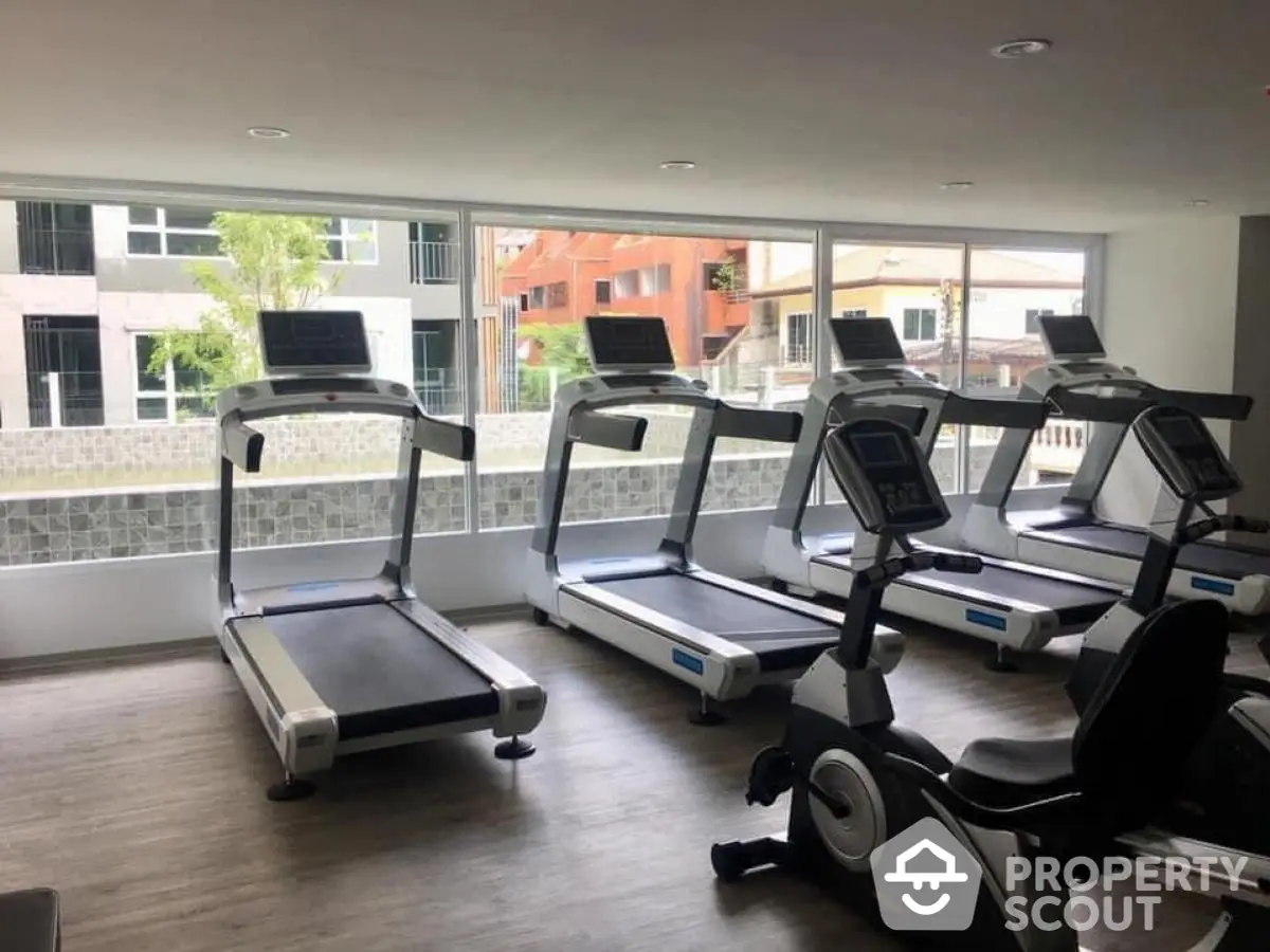 Modern gym with treadmills and exercise bike in a bright room with large windows.