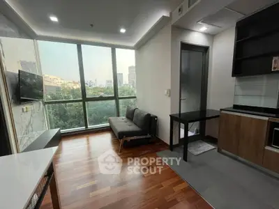 Modern living room with large windows and city view, featuring sleek furniture and wooden flooring.