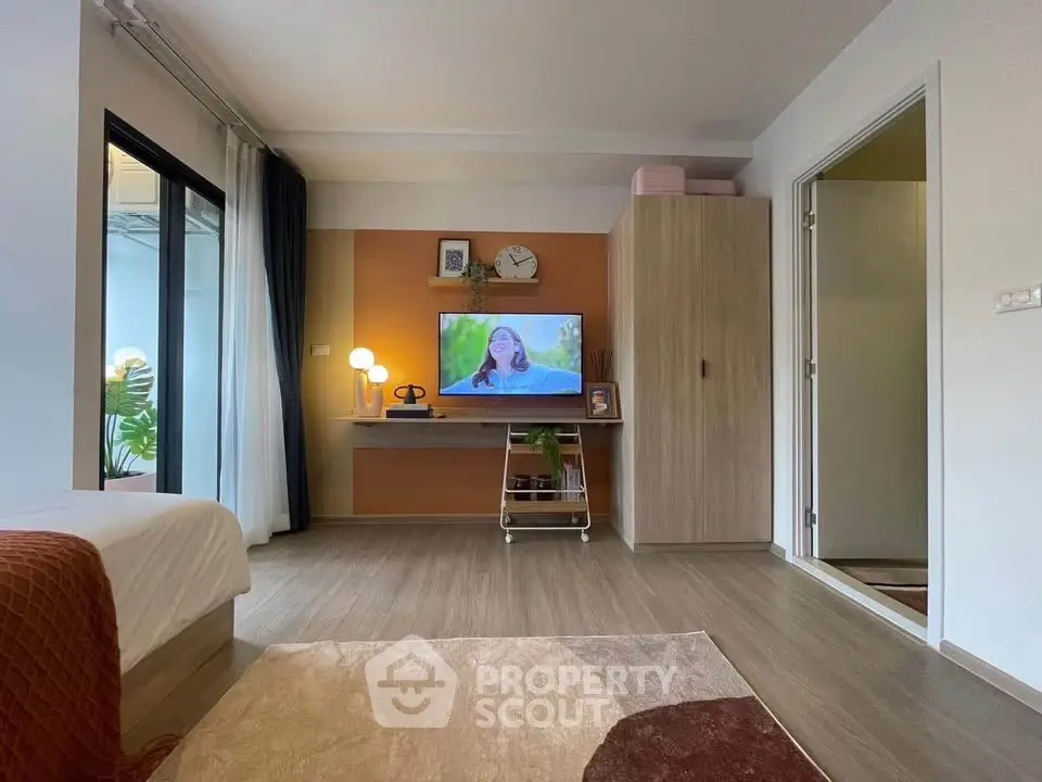 Modern living room with stylish decor and wall-mounted TV, featuring a cozy ambiance and sleek wooden flooring.
