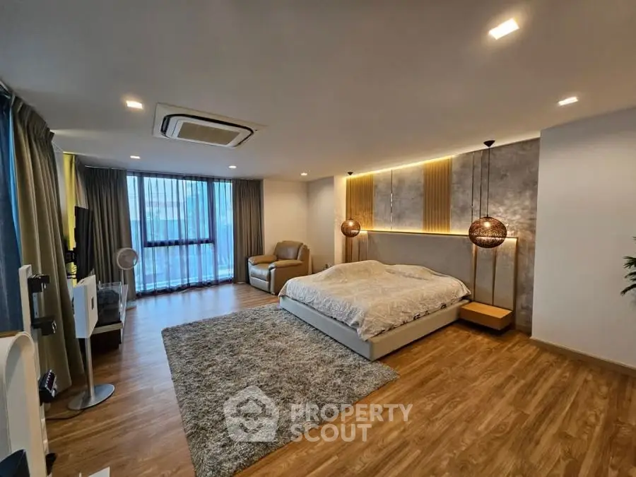 Spacious modern bedroom with elegant lighting and cozy seating area