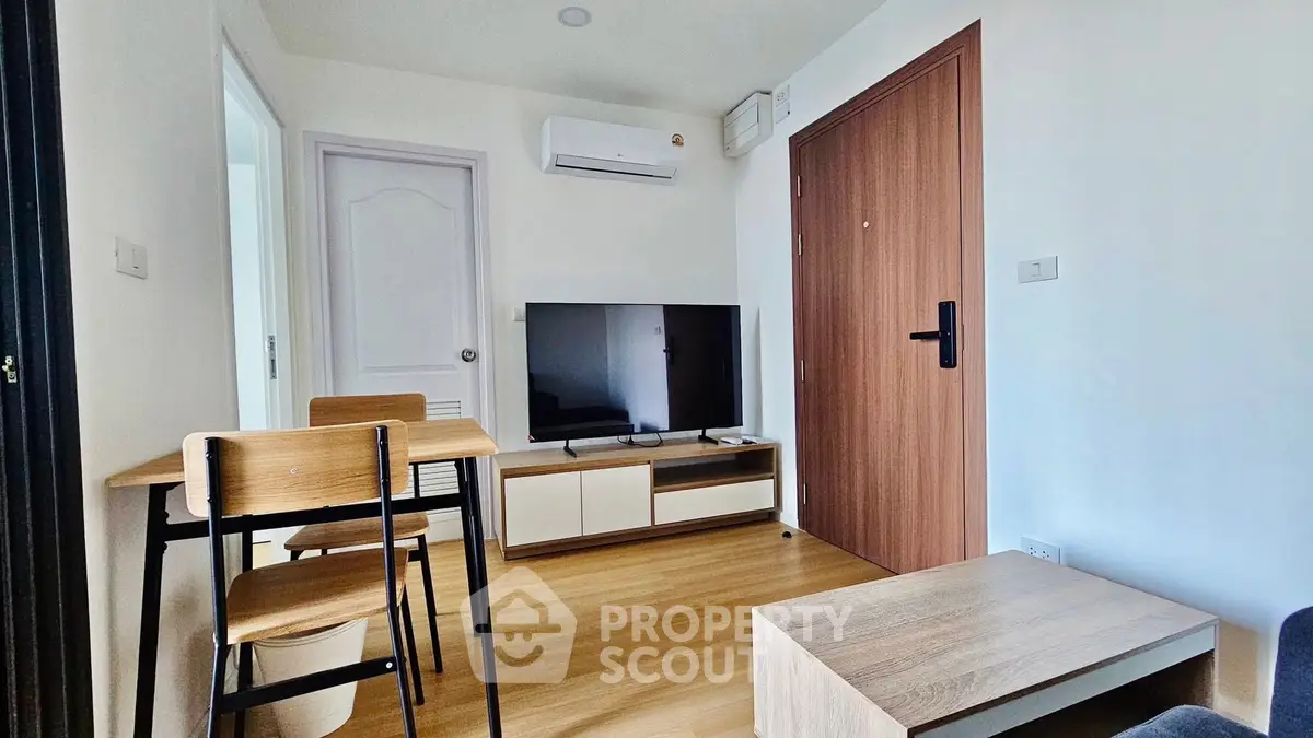 Modern living room with sleek furniture and wall-mounted TV in cozy apartment.