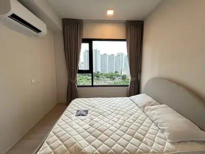 Modern bedroom with city view, featuring a cozy bed and air conditioning, ideal for urban living.