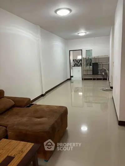 Spacious living room with modern sofa and sleek flooring, ideal for comfortable living.