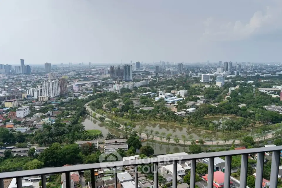 Stunning cityscape view from high-rise balcony overlooking lush greenery and urban skyline.