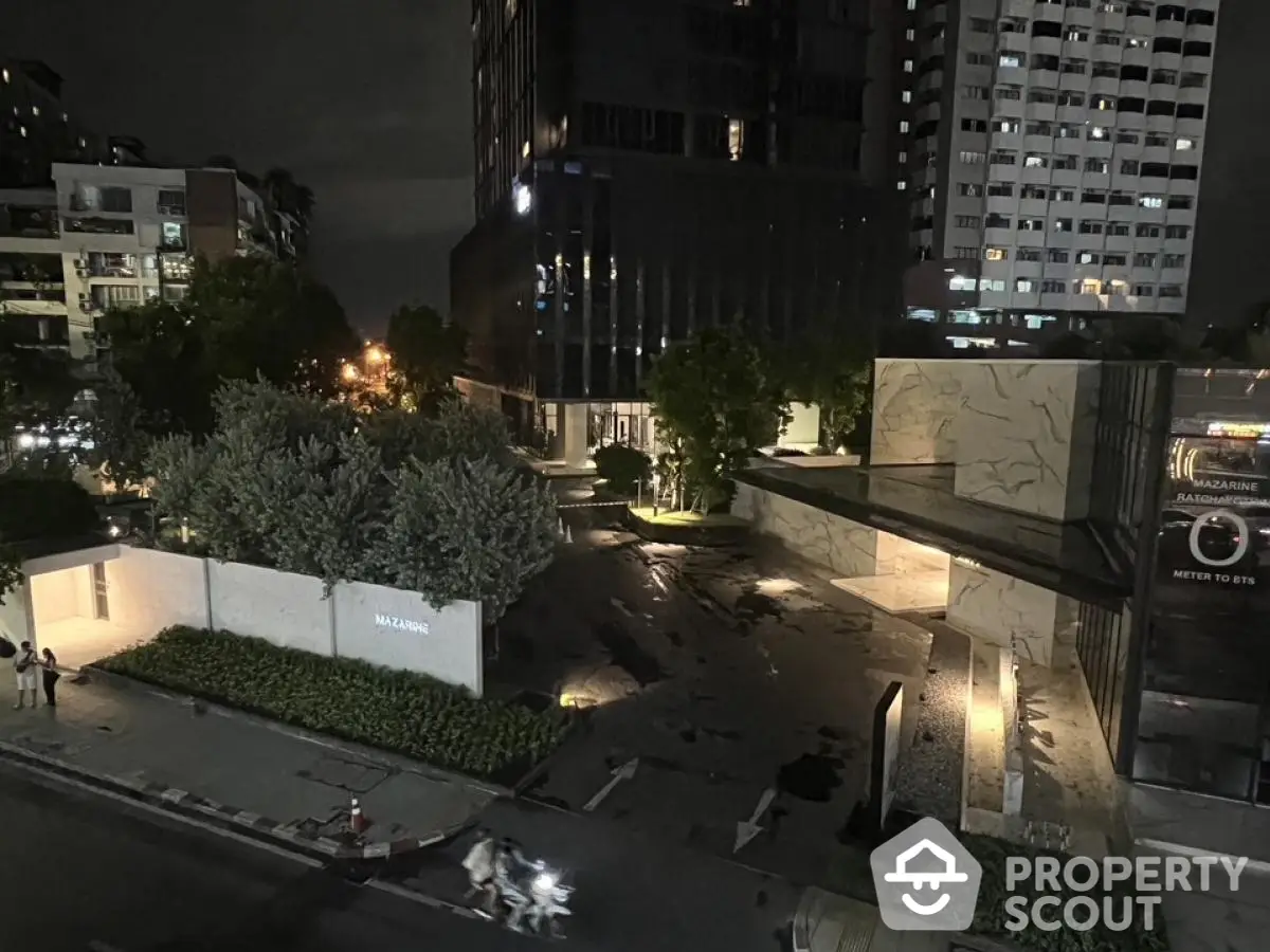 Night view of modern residential building entrance with landscaped garden.