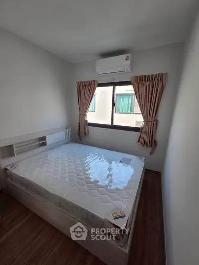 Cozy bedroom with air conditioning and natural light, featuring a comfortable bed and elegant curtains.