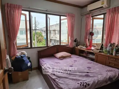 Cozy bedroom with large windows and pink curtains offering a bright and airy atmosphere.