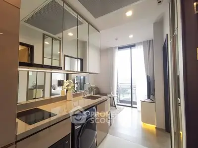 Modern kitchen with sleek appliances and open layout leading to a bright living area.