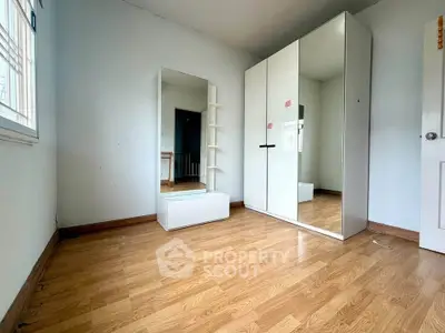 Spacious bedroom with wooden flooring and modern wardrobe in a bright, airy setting.