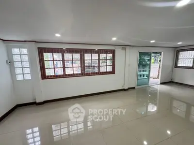 Spacious living room with large windows and glossy tiled floors, perfect for natural light and modern living.