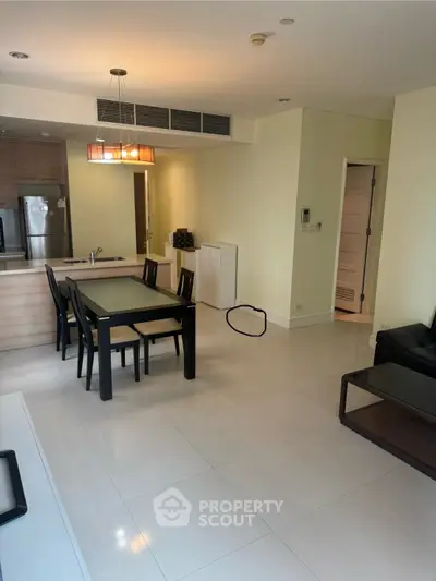 Modern open-layout living and dining area with sleek furniture and kitchen view.