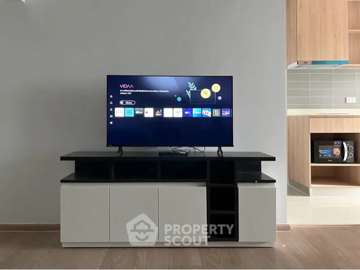 Modern living room with sleek TV stand and open kitchen layout, perfect for contemporary living.