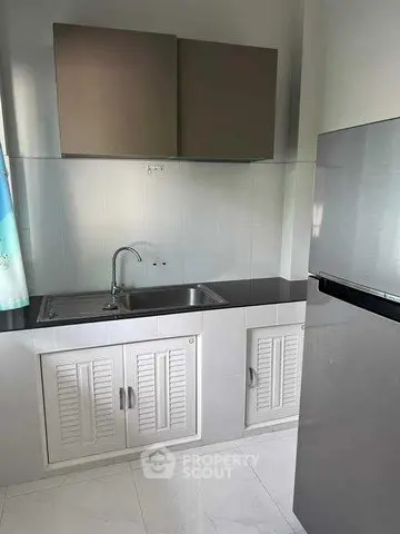 Modern kitchen with sleek cabinetry and stainless steel fridge in a compact layout.