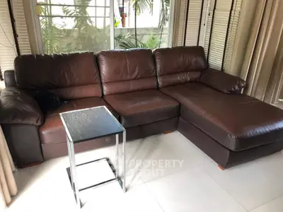 Spacious living room with elegant brown leather sectional sofa and modern side table, perfect for relaxation.